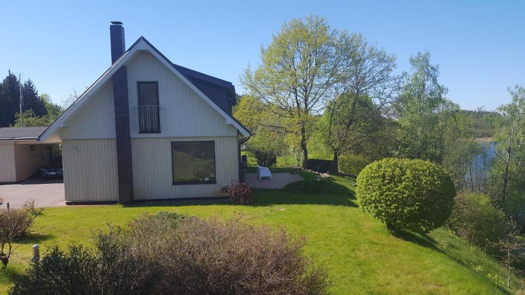 une maison blanche avec une cour avec de l'herbe et des buissons dans l'établissement Domido Villa, à Trakai