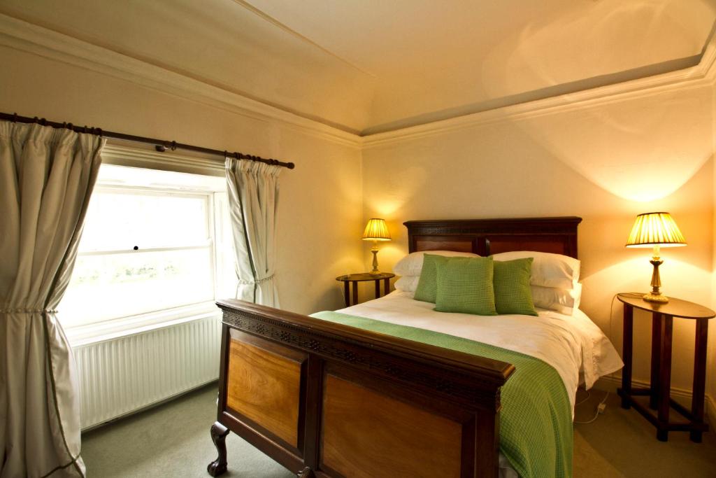 a bedroom with a bed with green pillows and a window at Clonacody House in Clonmel