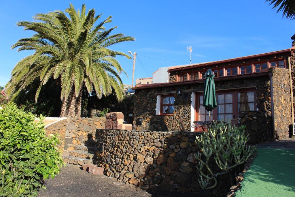 a building with a palm tree and a stone wall at Casas Anton & Maria in El Pinar del Hierro