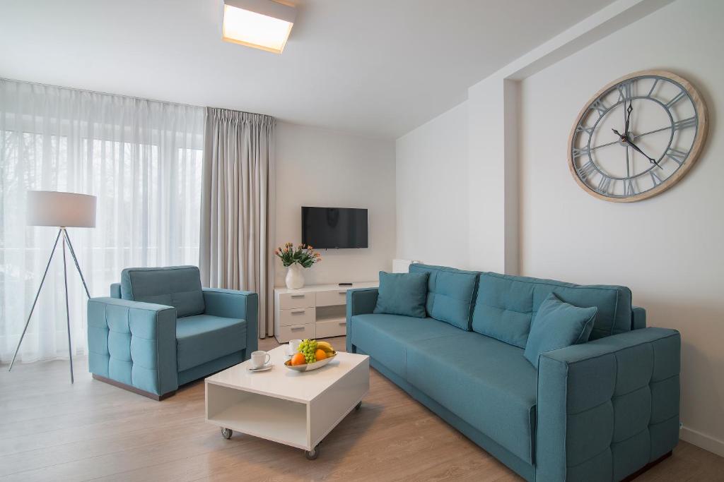 a living room with two blue couches and a clock at Apartament 65 Przy plazy in Władysławowo