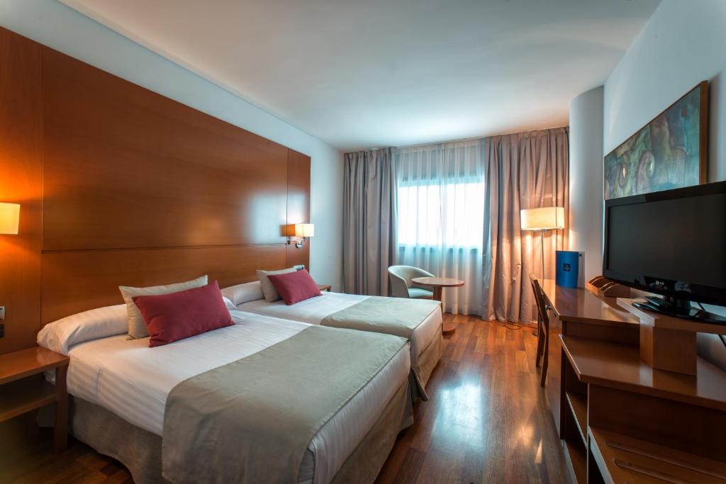 
a hotel room with two beds and a television at Hotel Azarbe in Murcia

