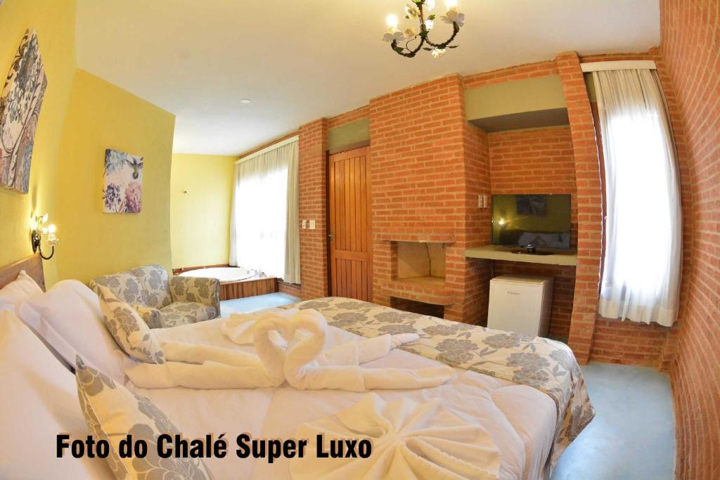 a hotel room with a bed, couch and a television at Pousada Villa dos Leais in Serra Negra