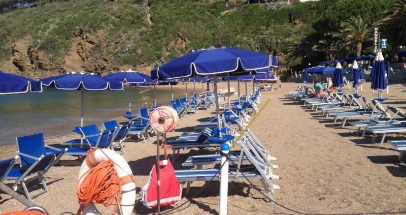 een stel stoelen en parasols op een strand bij Mandel Club in Capoliveri