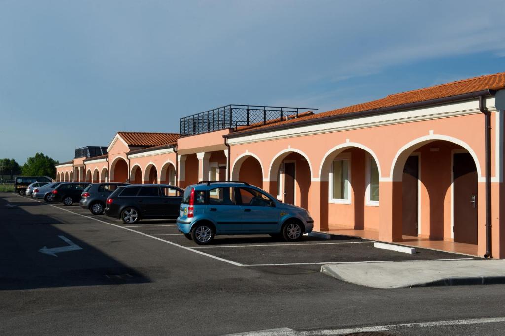 ミラーノにあるオートホテル ヴェネチアの建物の隣の駐車場に停車した青色の小型車