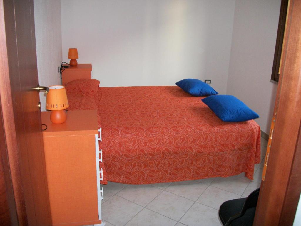 una camera con letto rosso e cuscini blu di Casa Solaria Villetta singola panoramicissima a Costa Rei