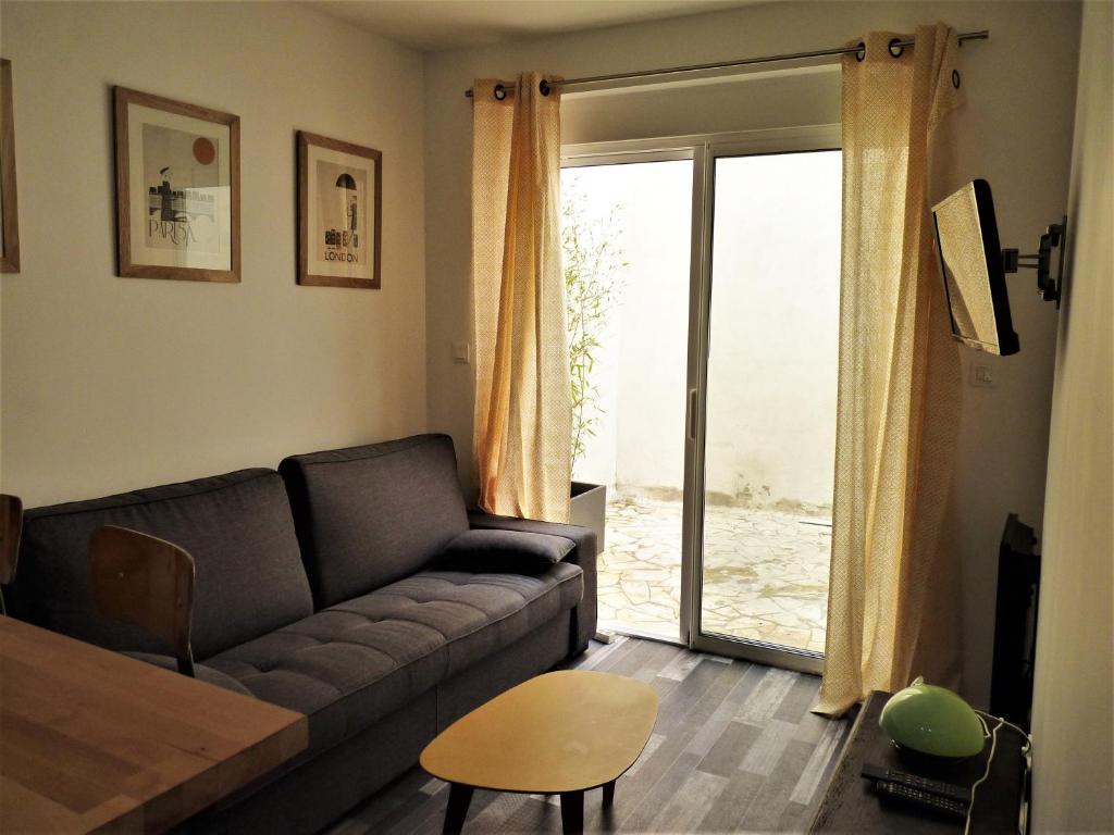 een woonkamer met een bank en een glazen schuifdeur bij Les Cloutiers in La Rochelle