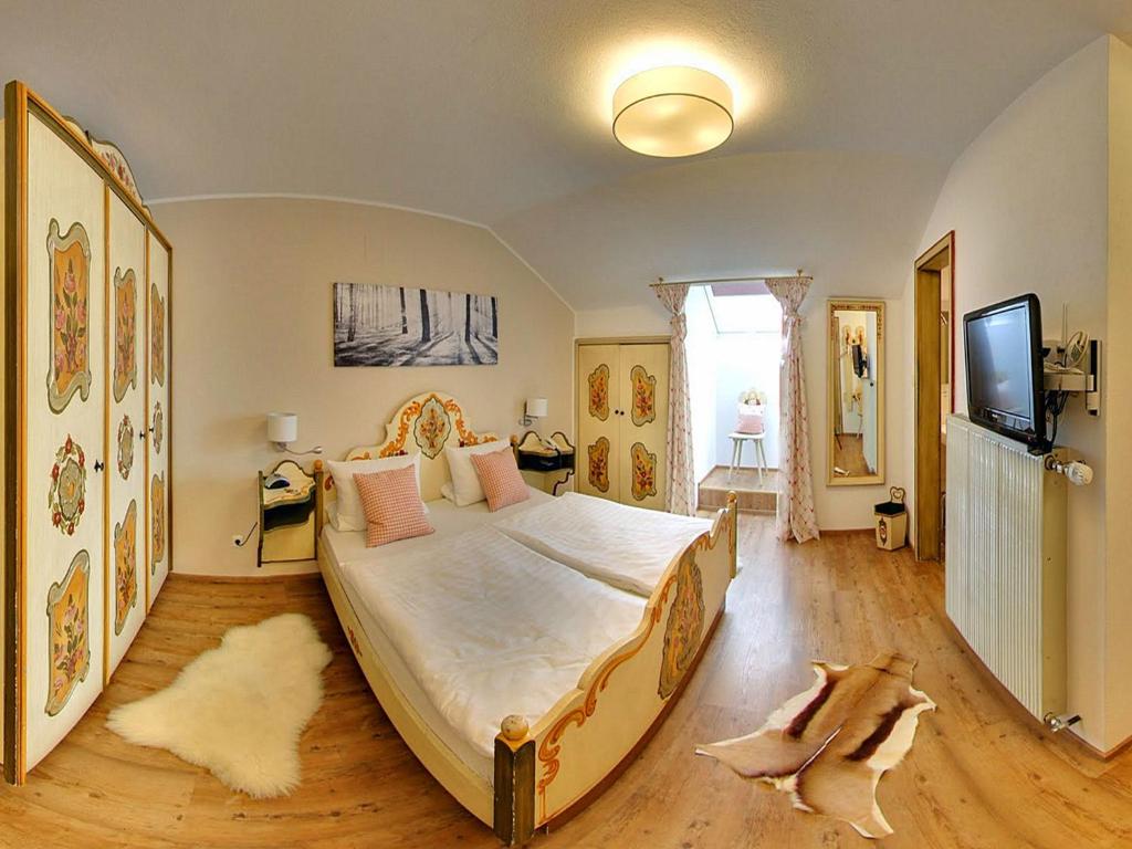 a bedroom with a large bed and a flat screen tv at Gasthof Alter Wirt in Bernau am Chiemsee