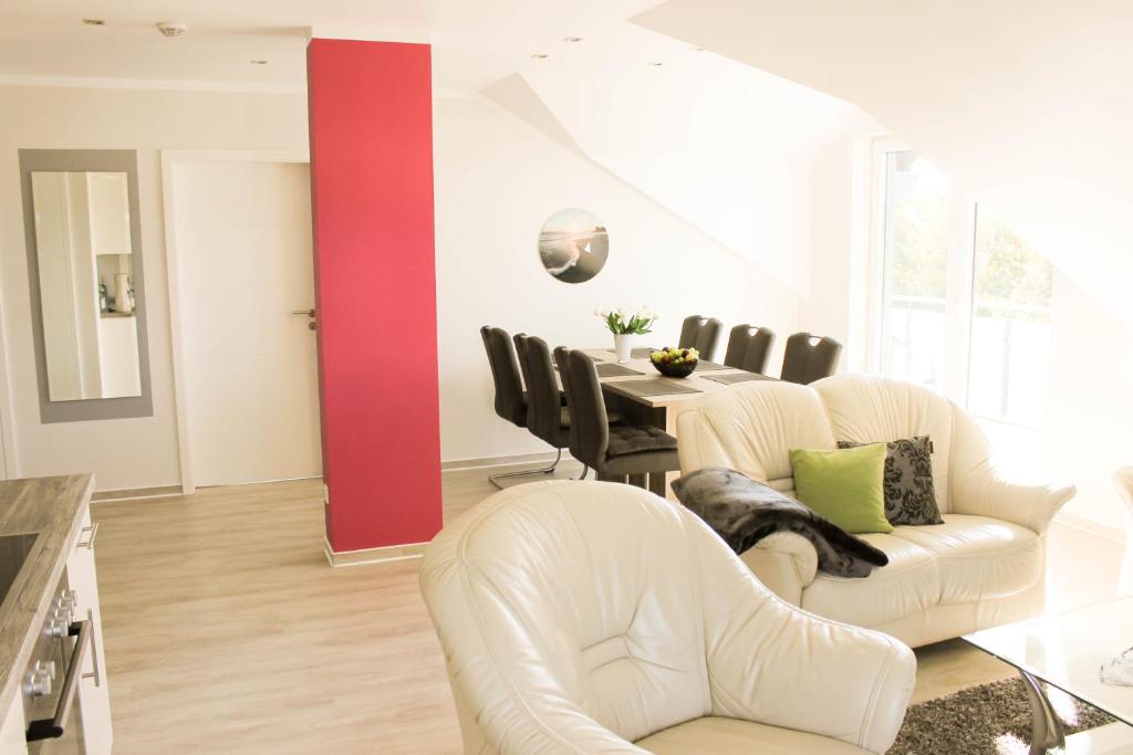 une salle à manger avec des chaises blanches et un mur rouge dans l'établissement Haus Feriendomizil, à Ahlbeck