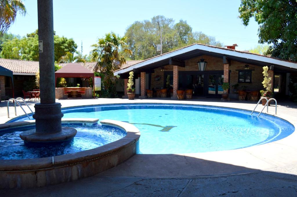 a swimming pool with a fountain in front of a building at Hotel El Rancho in Navojoa