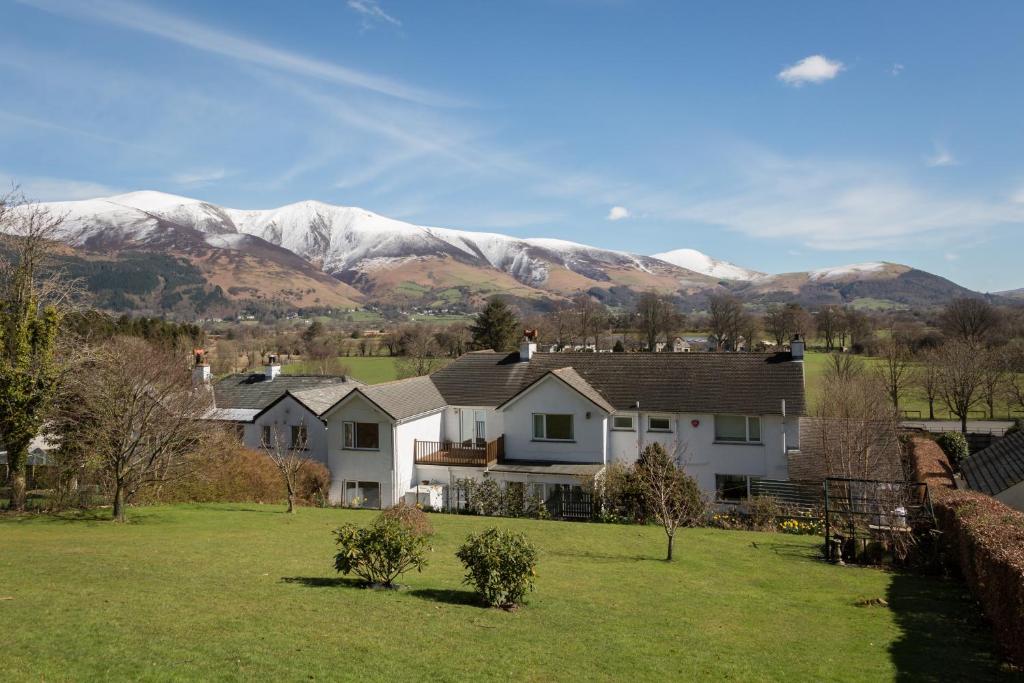 a house in a field with mountains in the background at Hermiston Guest House in Keswick