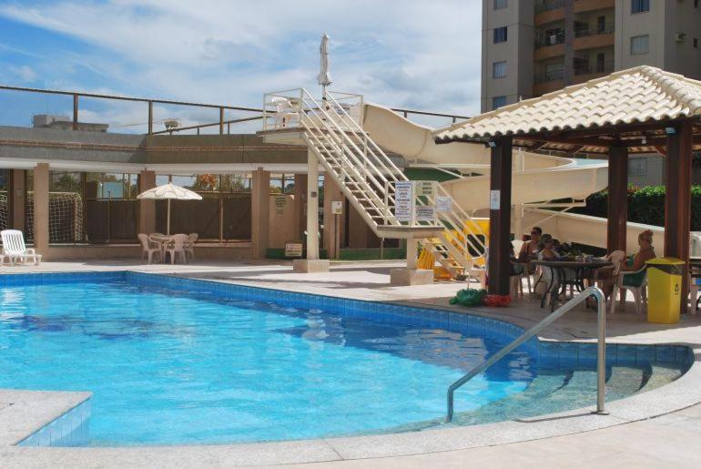 einen Swimmingpool mit Leuten, die an einem Tisch neben einem Gebäude sitzen in der Unterkunft Prive das Thermas I - 3 Quartos - Achei Ferias in Caldas Novas