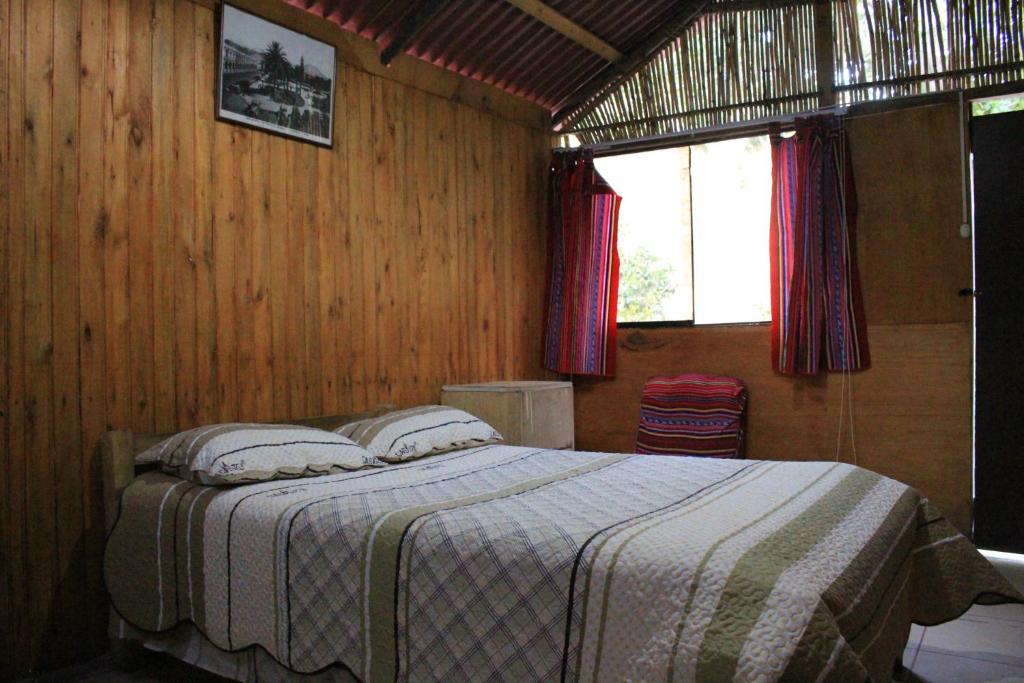 a bedroom with a bed in a wooden wall at Oasis Paraiso Ecolodge in Cabanaconde