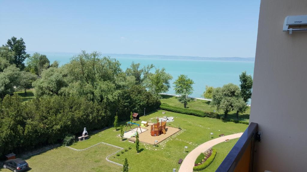 a view of a park with trees and the water at Milan Apartmanok in Siófok