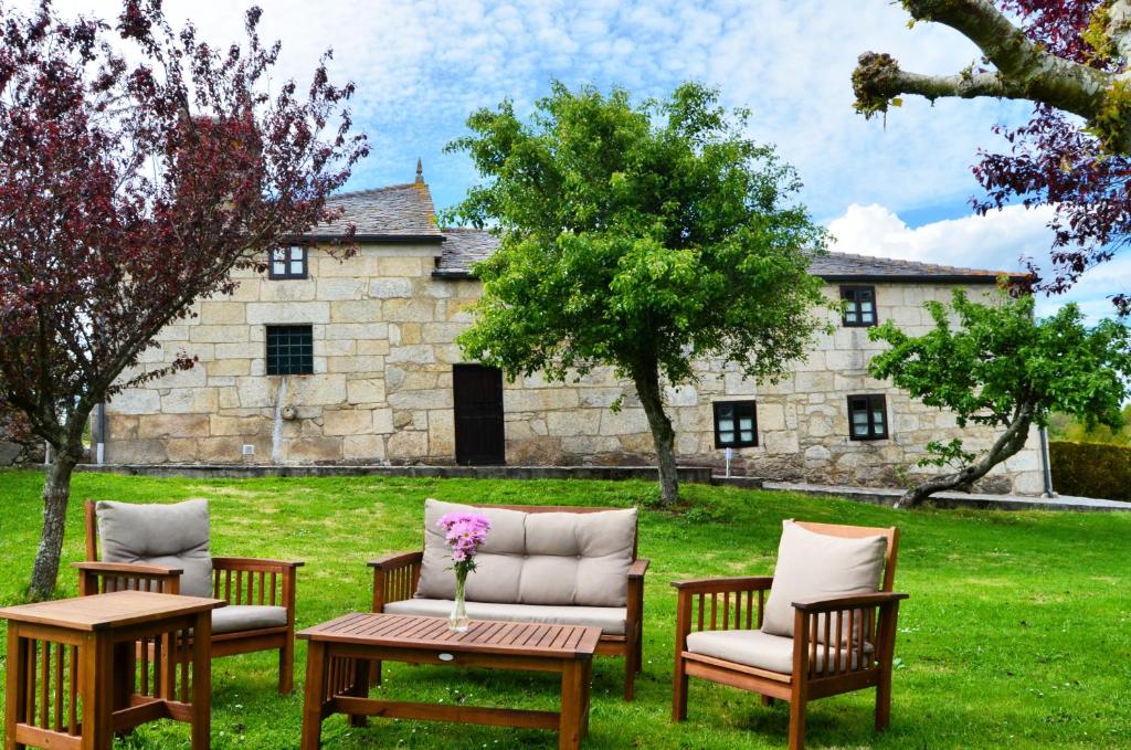 a group of chairs and tables in front of a building at Casa de Martiño in Friol