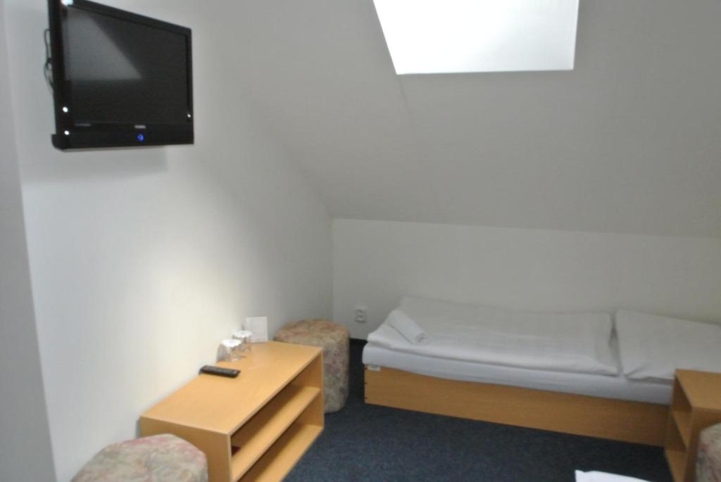 a small room with a bed and a tv on the wall at Hotel Širák in Most