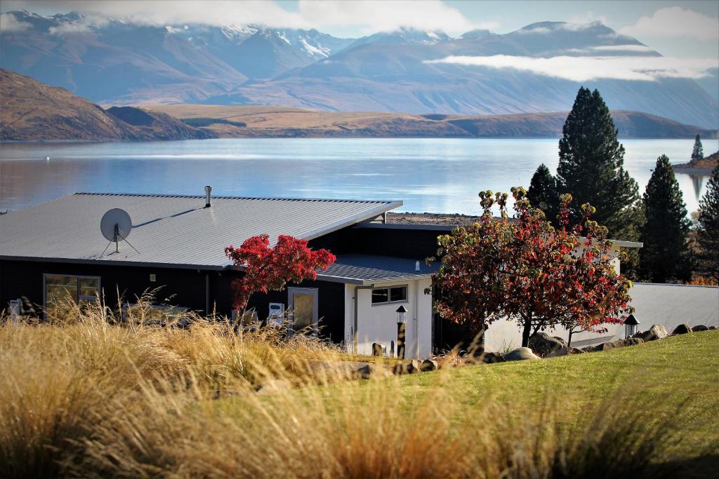 een huis met uitzicht op een meer en de bergen bij Tekapo Sky Lodge in Lake Tekapo