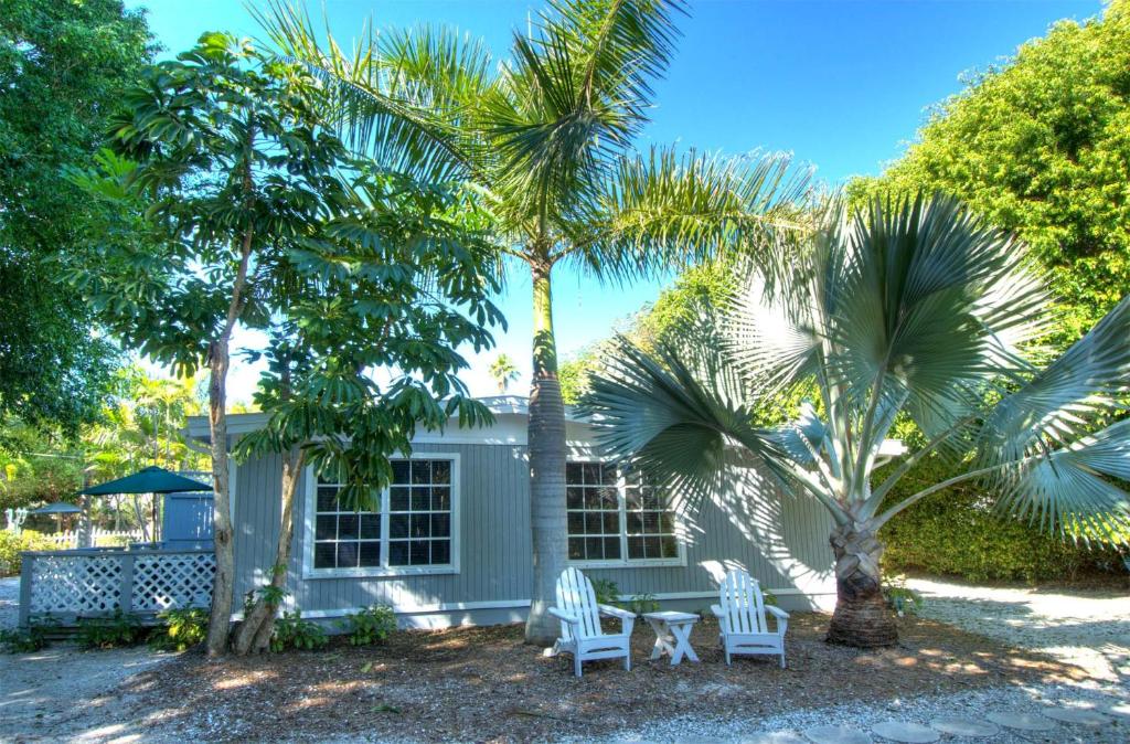 a house with two palm trees and a table and chairs at Seahorse Cottages - Adults Only in Sanibel
