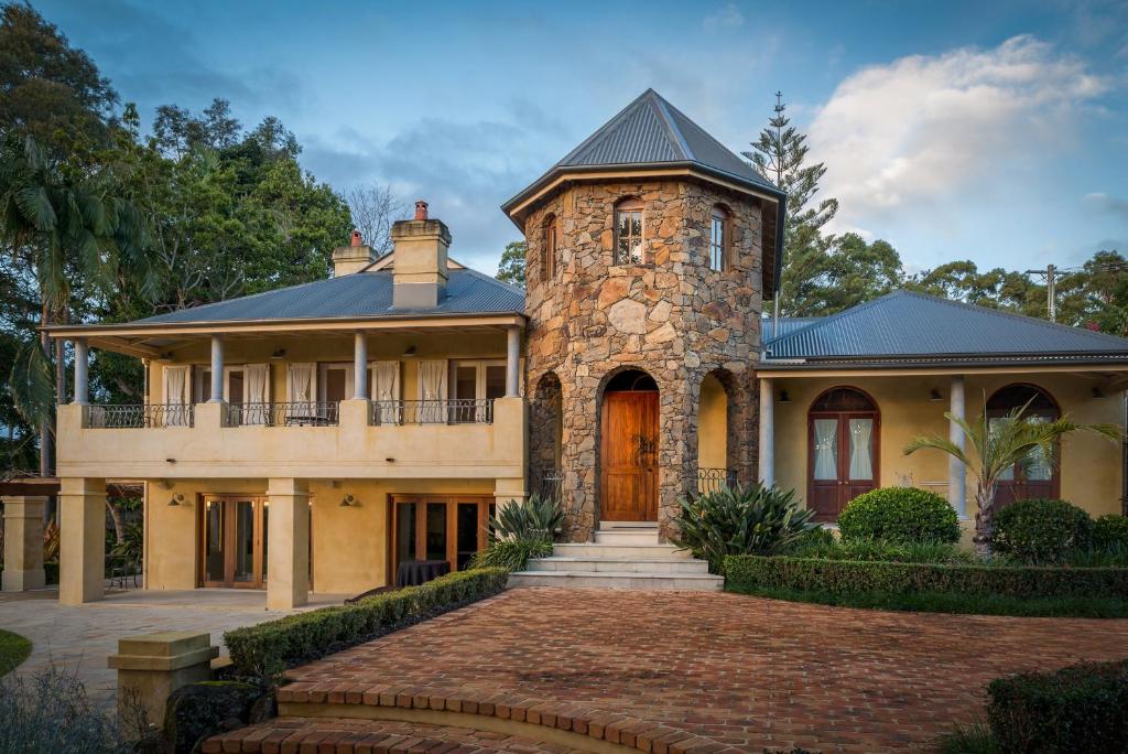 a large stone house with a turret at Victoria's At Ewingsdale in Byron Bay