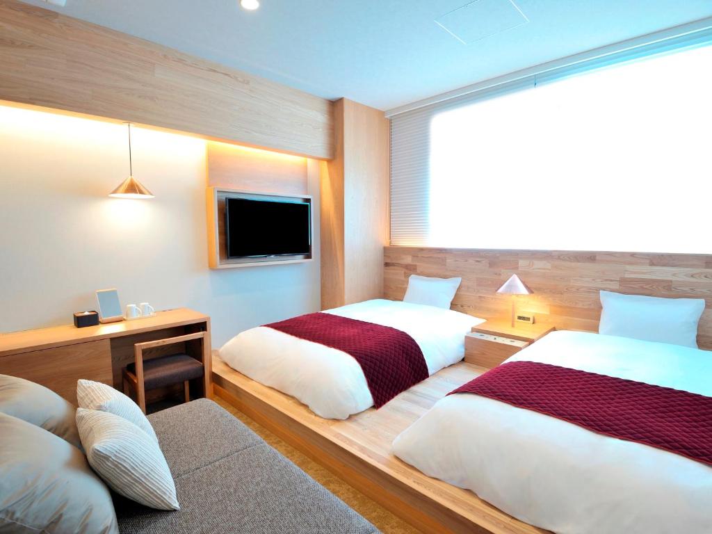 een hotelkamer met 2 bedden en een televisie bij hotel androoms Osaka Hommachi in Osaka