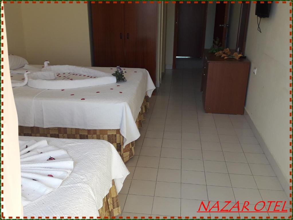 two beds in a room with white towels on them at Nazar Hotel in Didim