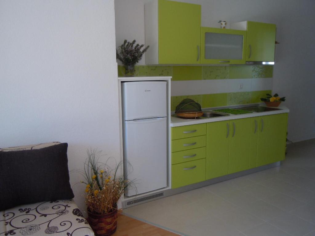 a kitchen with green cabinets and a white refrigerator at Apartments Tri sestrice in Sveta Nedelja