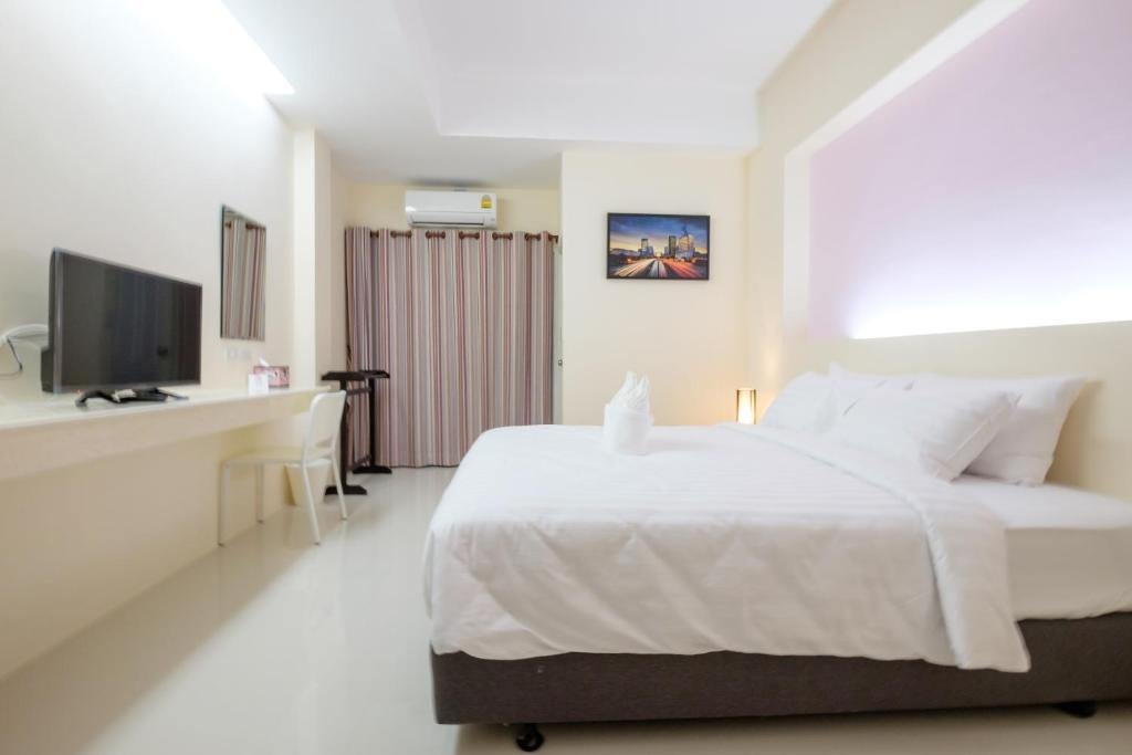 a white bedroom with a bed and a television at Wisdom Hotel in Samut Songkhram