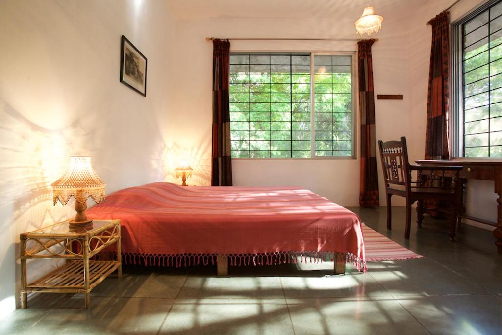 a bedroom with a red bed and a window at The Annex, Isai Ambalam guest house in Auroville