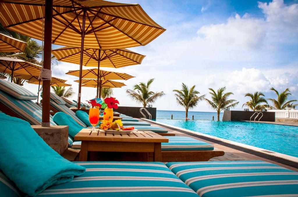 a resort with a pool with chairs and umbrellas at Champa Resort & Spa in Phan Thiet