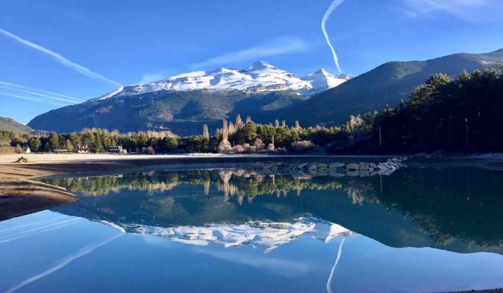 a mountain reflecting in the water in front of a lake at Roca Nevada Resort in Villanúa