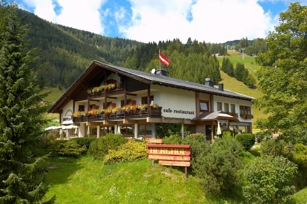 a building on a hill with a bench in front of it at Schi- und Wanderhotel Berghof in Bad Kleinkirchheim