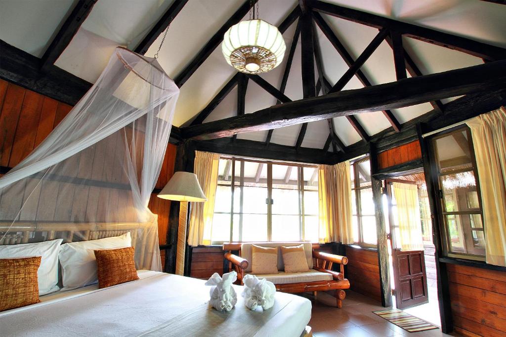 sypialnia z łóżkiem i kanapą w pokoju w obiekcie Pung-Waan Resort w mieście Sai Yok