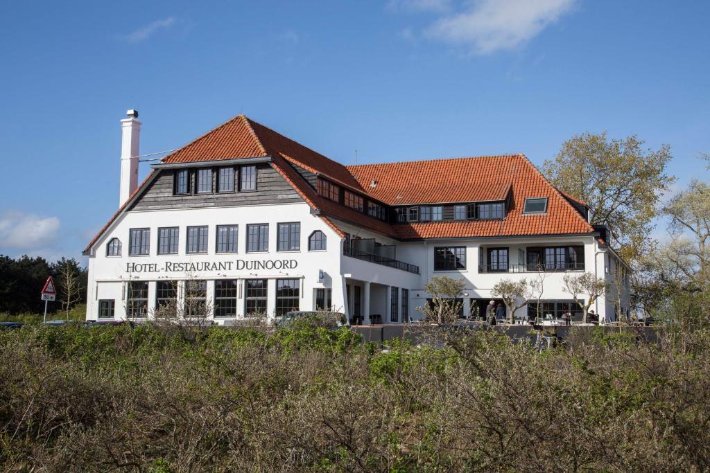 a large white building with an orange roof at Fletcher Boutique Hotel Duinoord in Wassenaar