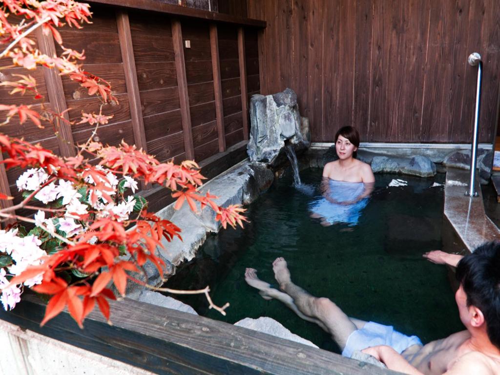 two people in a pool of water in a spa at Kirishima miyama hotel in Kirishima