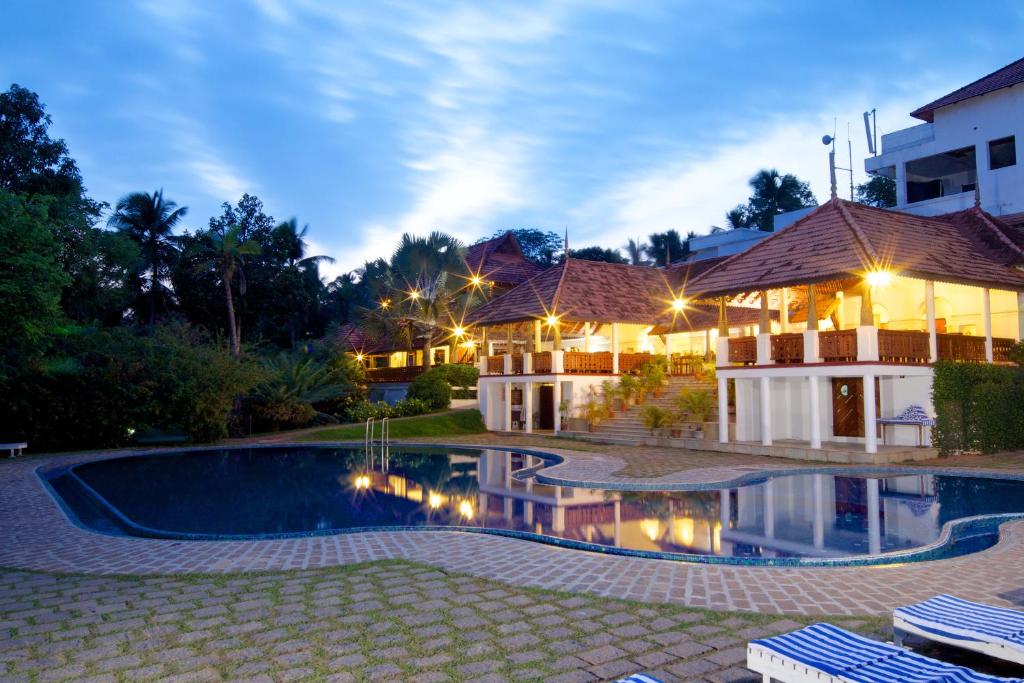 a swimming pool in front of a house at night at The Travancore Heritage Beach Resort in Kovalam