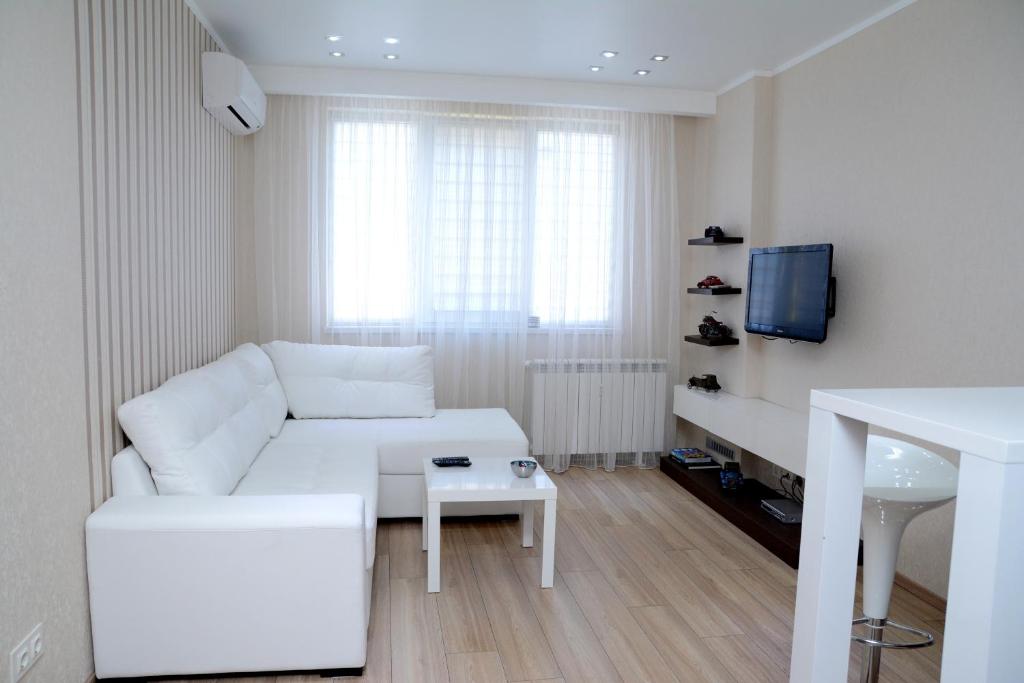 a white living room with a white couch and a tv at Apartment SOFIA in Sofia