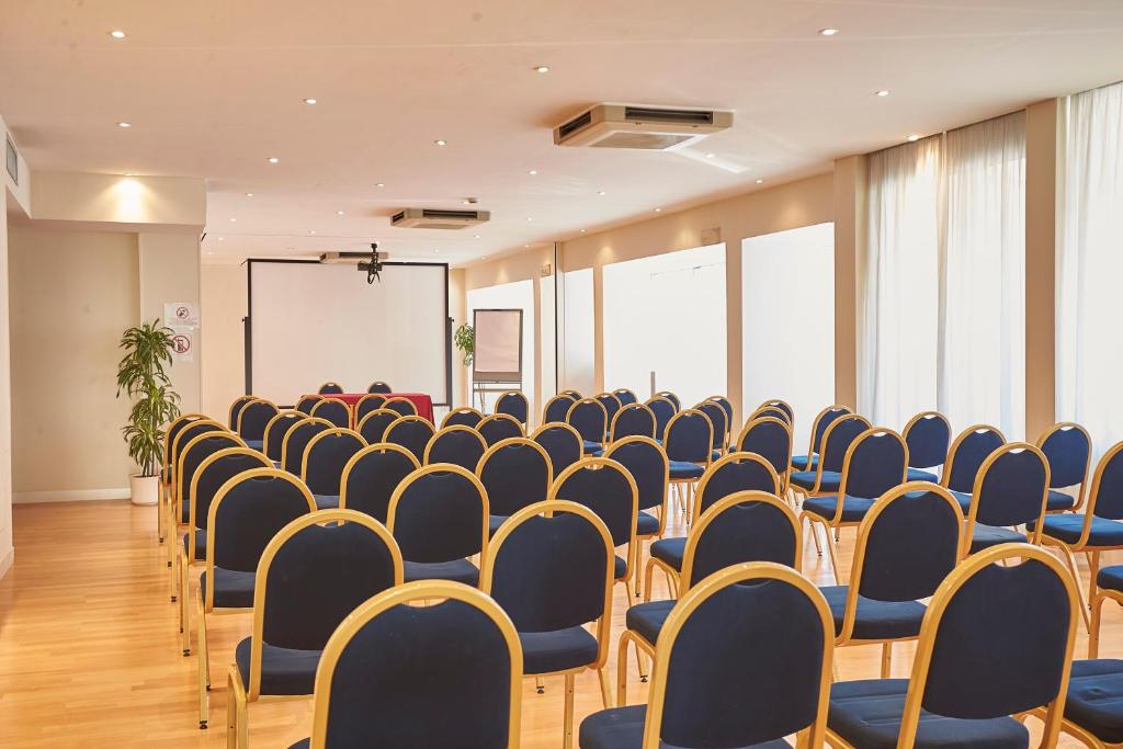 an empty room with chairs and a screen and a podium at Hotel Sina Astor in Viareggio
