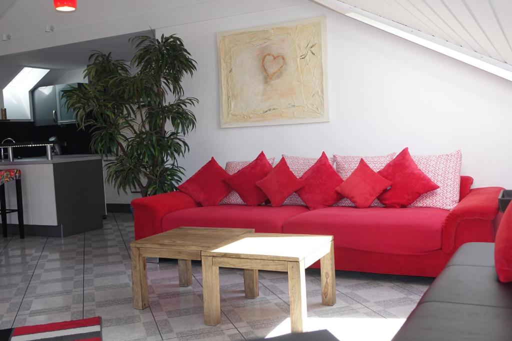 un sofá rojo con almohadas rojas en la sala de estar. en Seeblick Kampf mit Fahrradgarage, en Nonnenhorn