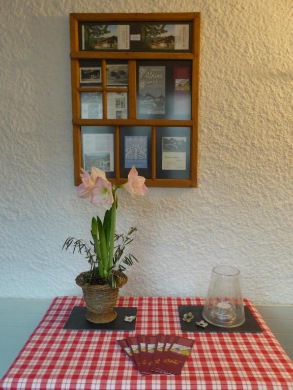 a table with a red and white checkered table cloth and a flower at Pension Alpina in Lenk