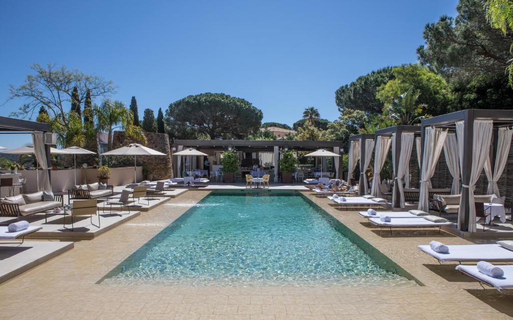 una piscina con sedie a sdraio e ombrelloni di MUSE Saint Tropez - Small Luxury Hotels of the World a Saint-Tropez