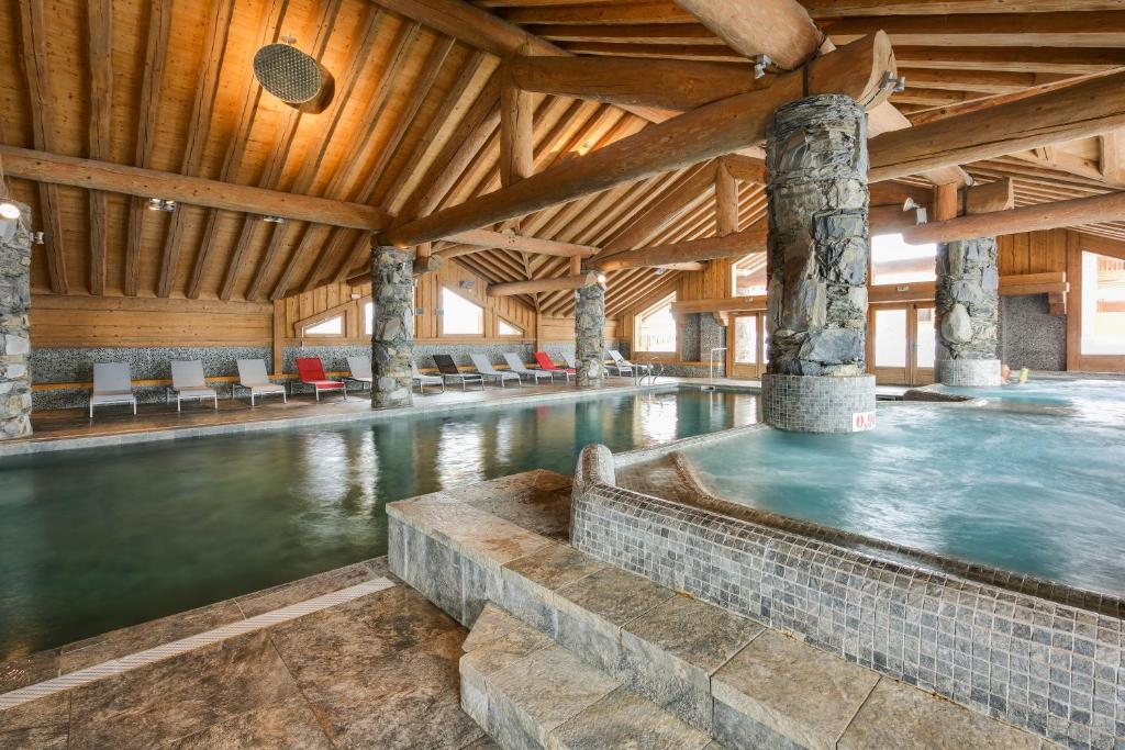 una piscina cubierta en un edificio de madera con piscina en CGH Résidences & Spas Les Cimes Blanches, en La Rosière