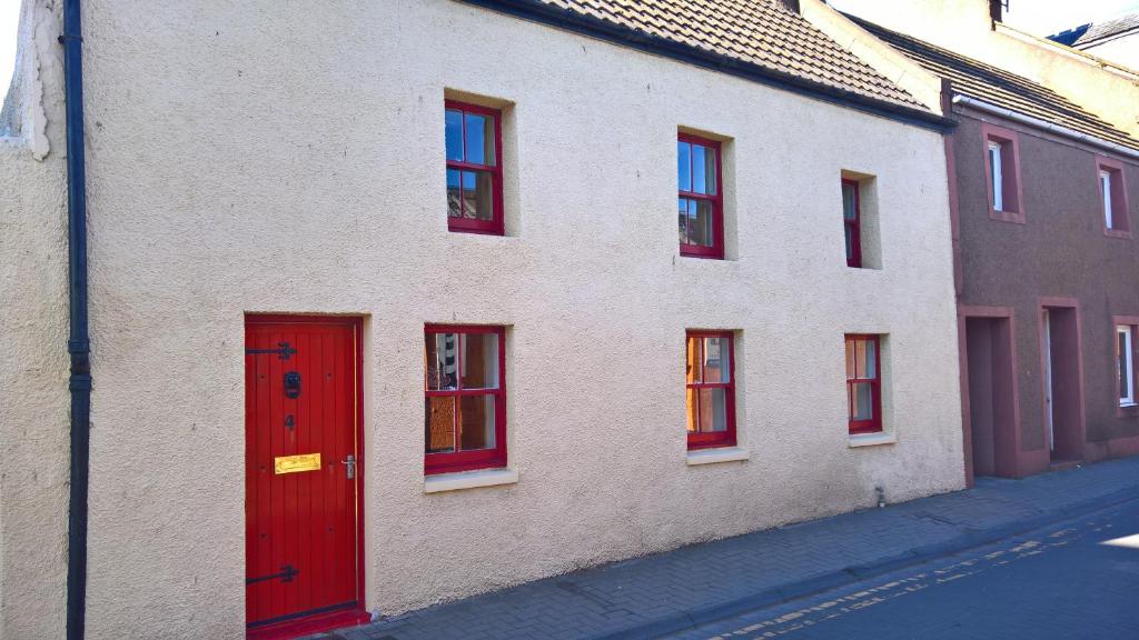 a building with red doors and windows on a street at The Wee Anchor in Arbroath