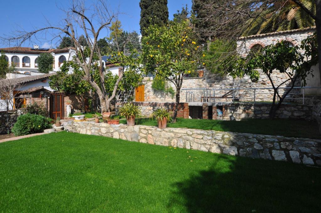 a yard with a stone wall and green grass at Garden House in Selçuk