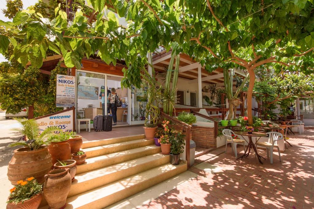 an outdoor patio area with benches and trees at Nikos Hotel in Matala