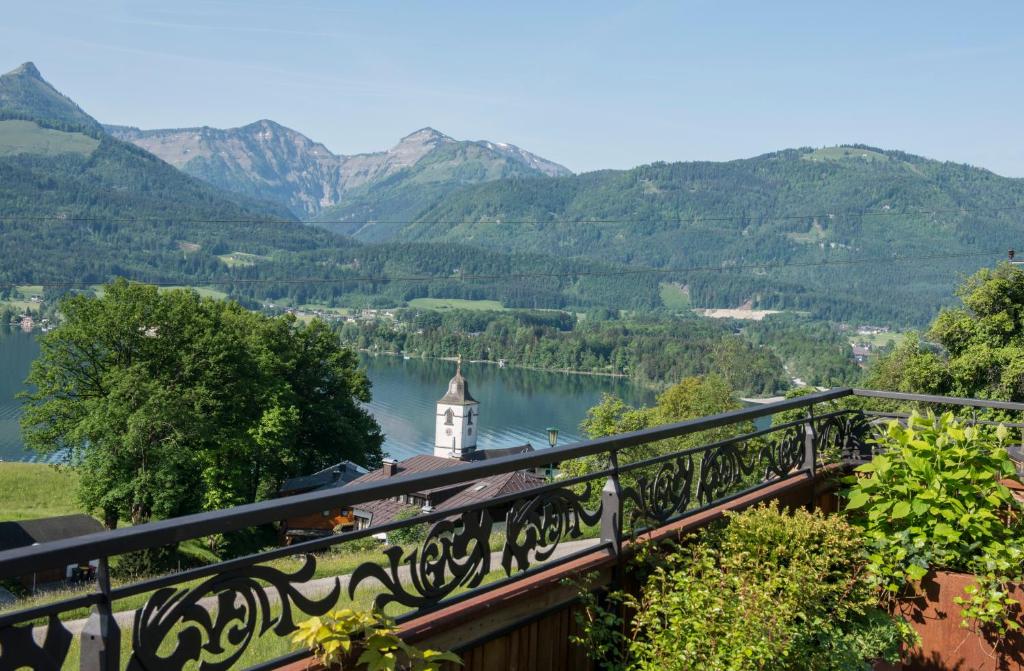 a view of a lake with a clock tower and mountains at The View in St. Wolfgang