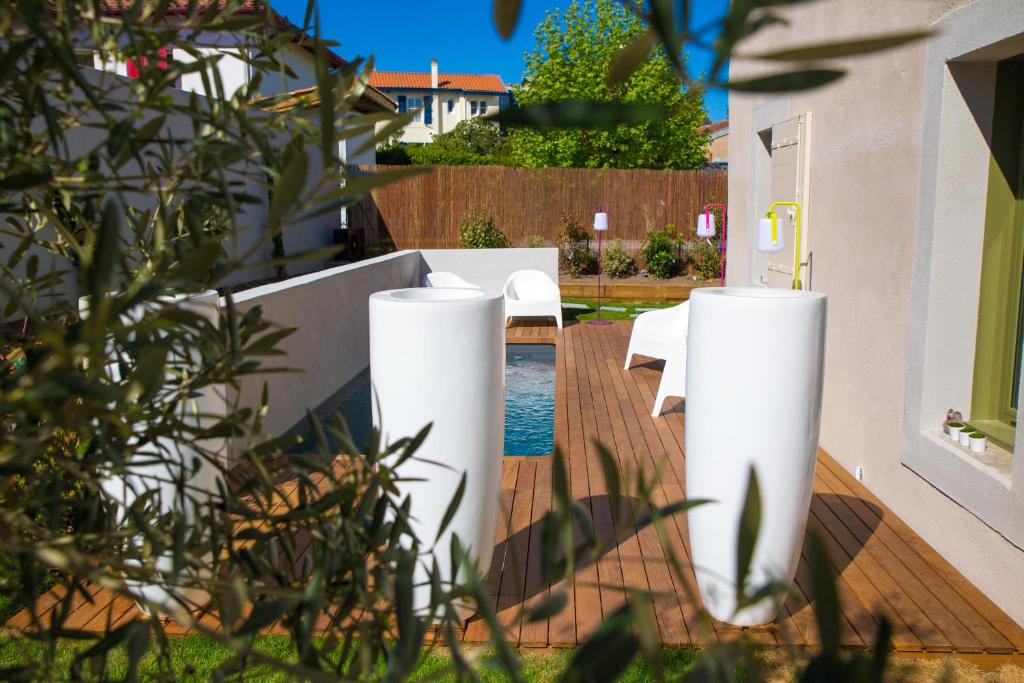 dos jarrones blancos sentados en una terraza de madera en Chambre d'Hôtes Arima, en Biarritz