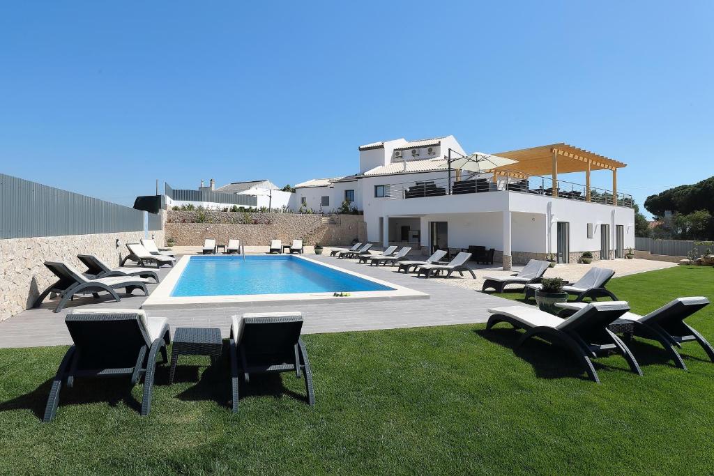 a group of chairs and a swimming pool in front of a house at Sunfield Guest House - Only Adults in Albufeira