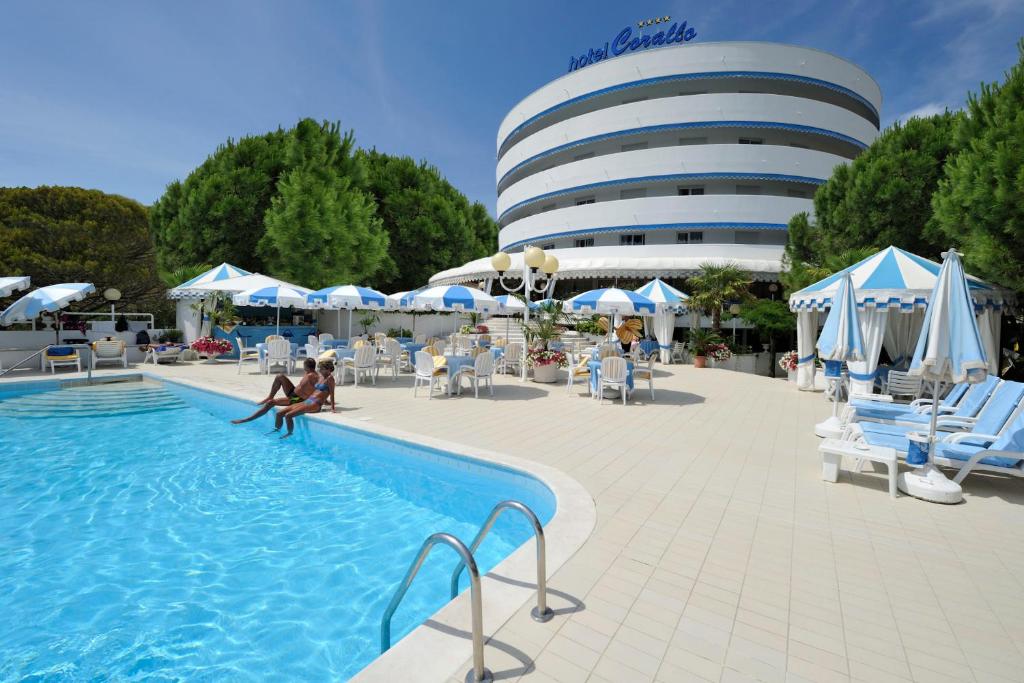 una piscina con un edificio sullo sfondo di Hotel Corallo a Bibione