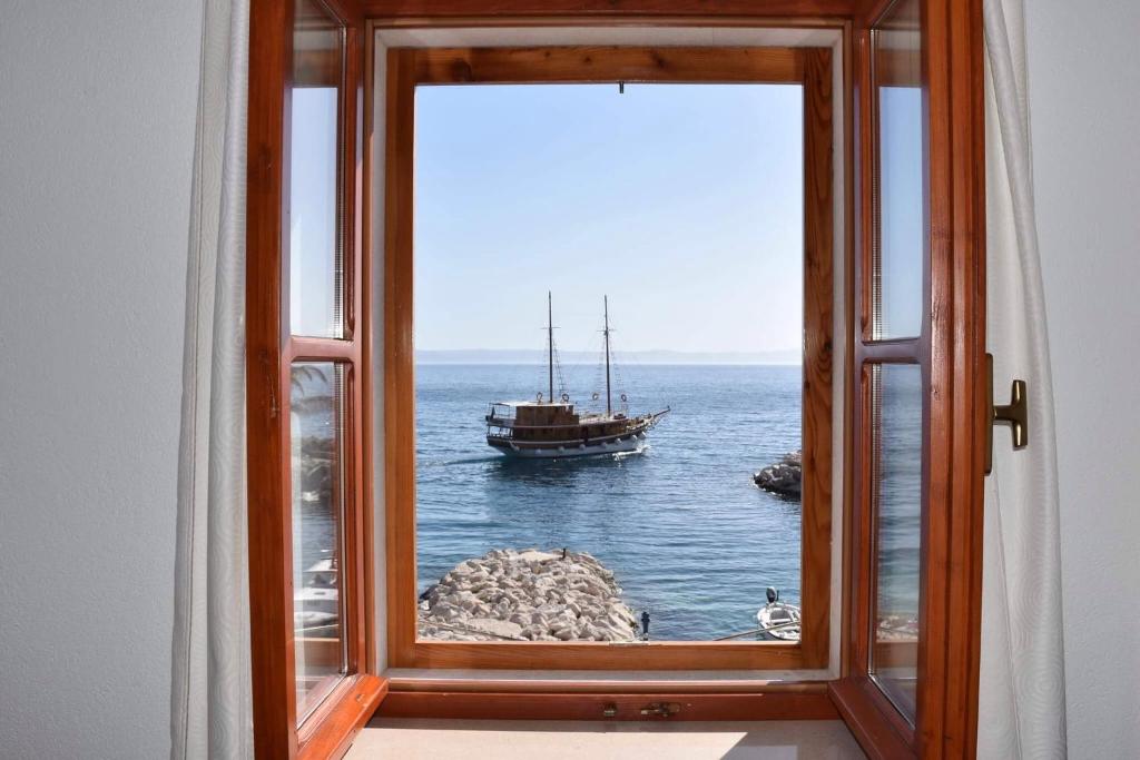 a window with a view of a boat in the water at Oldhouse Tučepi in Tučepi