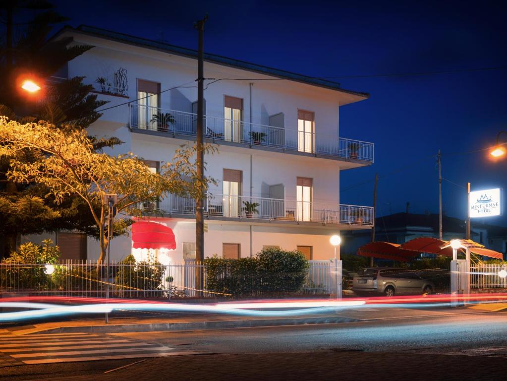 a white building at night with a street at Minturnae Hotel in Scauri