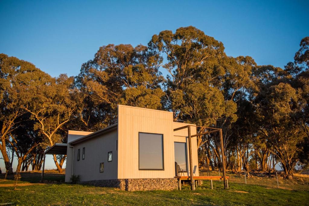 ein modulares Haus mit einer Bank vor Bäumen in der Unterkunft Dragonfly Cottages in Orange